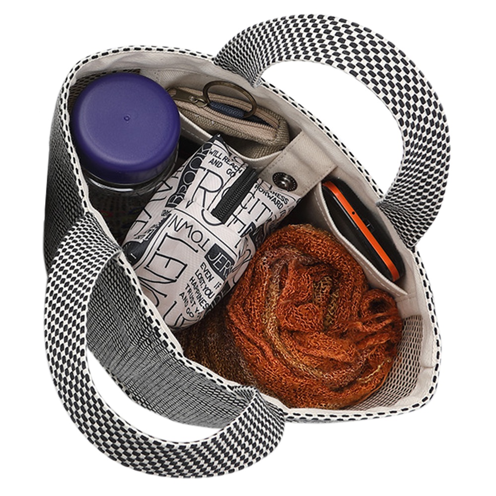 黑色與白色格子圖案的三河木綿刺子織圓底水桶包，內部裝有紫色瓶裝物、印有文字的白色化妝包、橘色毛料圍巾及黑色手機。