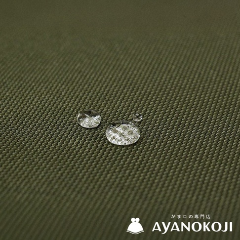 品牌Logo AYANOKOJI，搭配水珠在綠色斜紋布料上的特寫，展現布料的潑水機能。