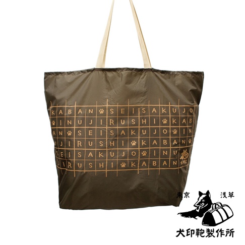 深棕色環保折疊收納購物袋，材質為尼龍，帶有米色提把。袋身正面印有淺棕色的文字與狗爪圖案組成的格子設計。