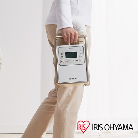 手持白色與金色邊框的 IRIS OHYAMA 被褥乾燥機，機身設有顯示螢幕及多個日文功能按鍵，搭配白色伸縮風管。