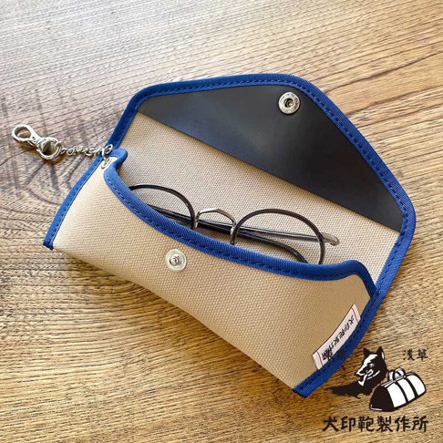 犬印鞄製作所純綿帆布眼鏡收納盒，淺卡其色搭配藍色滾邊，內有眼鏡，附有鑰匙圈和品牌標籤
