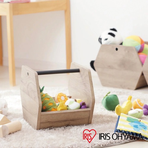 木質收納盒內裝著仿真水果玩具，包含鳳梨、橘子、蘋果、香蕉等，收納盒帶有黑色提把，整體為淺木色。