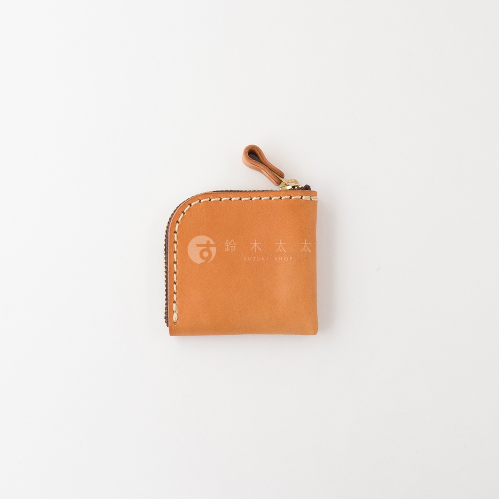 一個採用焦糖色皮革製成的職人手作方形拉鍊零錢包，表面印有鈴木太太標誌，包體採用 L 型拉鍊設計，邊緣以淺色線材手工縫製，頂部附有一個小巧的皮革拉環。