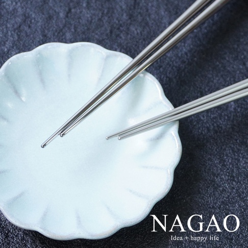 兩雙燕三条不鏽鋼筷，銀色，光滑表面，筷子末端呈圓形，置於淺藍色花瓣形狀的陶瓷碟上。