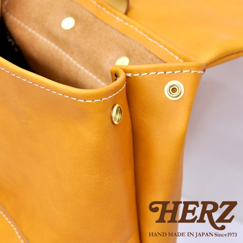 職人手作皮革後背包，展示部分為芥末黃色皮革，搭配白色縫線及金色鉚釘，材質為厚實皮革。