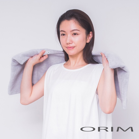 一位女性使用灰色吸水毛巾包裹頭髮，毛巾材質為柔軟的棉質，邊緣有按扣設計。