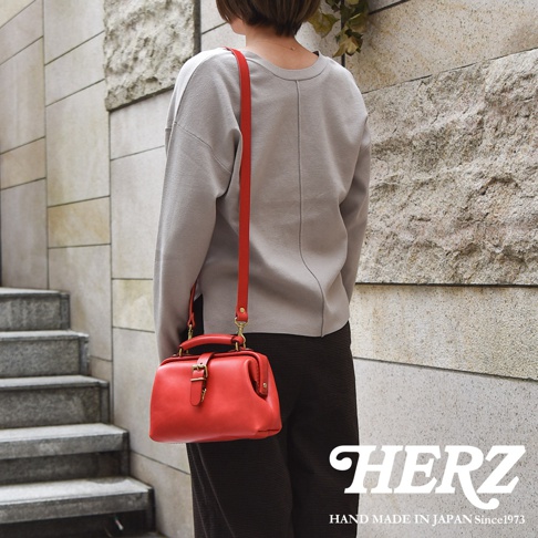 紅色皮革迷你軟皮杜勒斯包，配有紅色皮革肩帶和金色扣環，由職人手工製作。