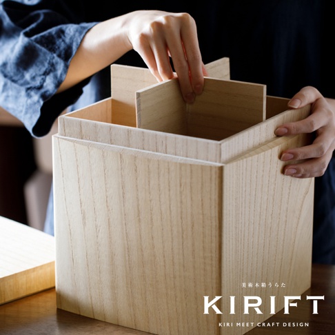 淺色桐木製收納箱，箱體呈現自然木紋，內部有可拆卸的木製隔板，展示一雙手正在調整隔板。