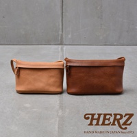 兩個皮革手拿包，一個為淺棕色，一個為深棕色，皆為職人手作。