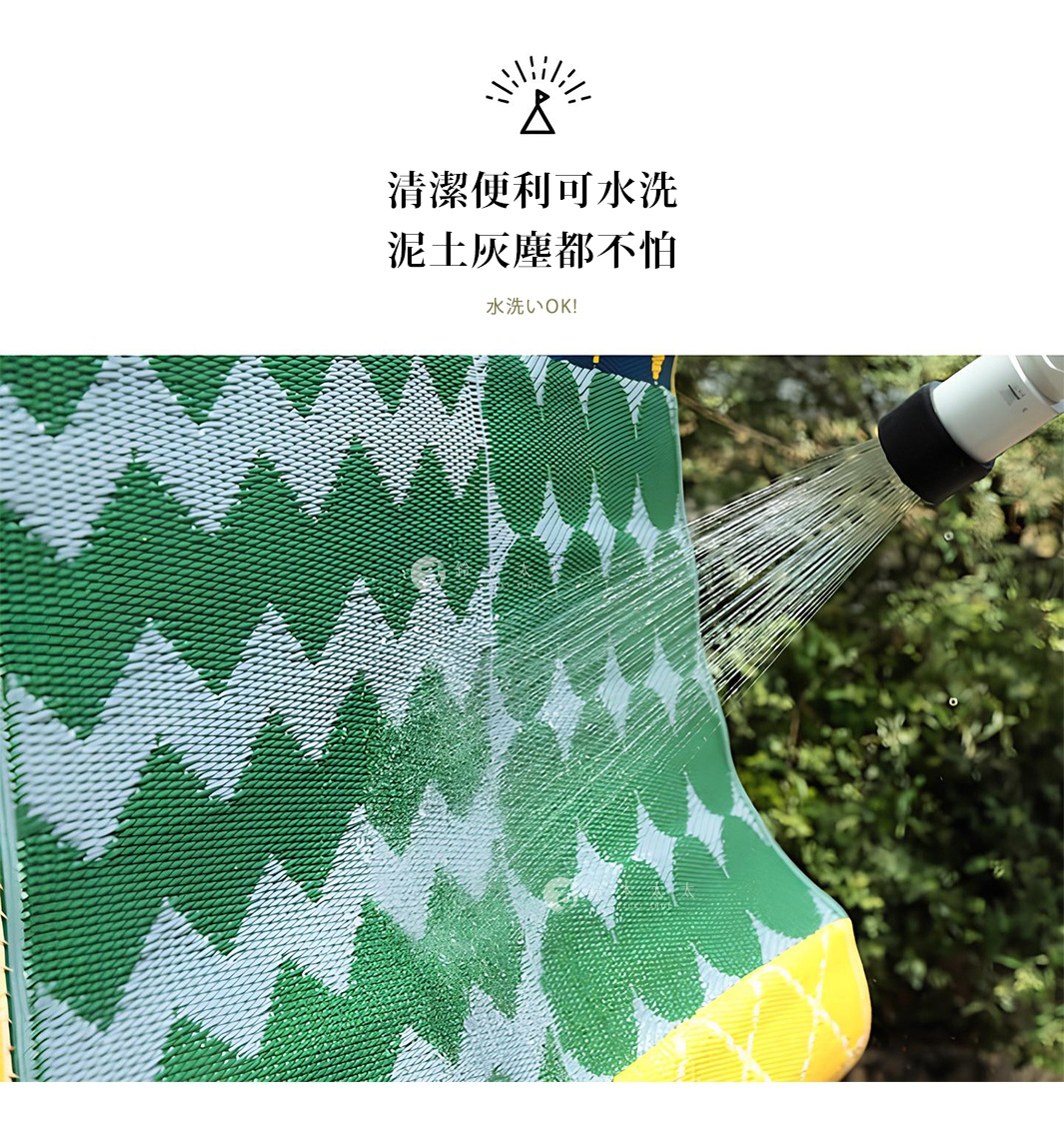 防水 PP 收納野餐墊，綠色與白色相間的鋸齒狀圖案，材質表面正被水柱沖洗，顯示其易於清潔的特性，背景為綠色植物。