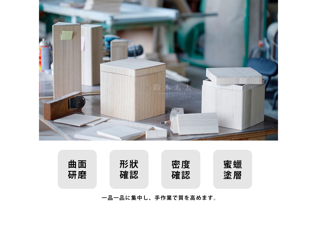 數個淺色桐木製收納箱，其中一個箱子蓋子打開，露出內部。箱子擺放在木製工作檯上，旁邊有木工刨刀和幾塊木板。