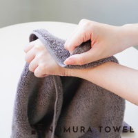 野村毛巾 YABAI 水漾瞬吸厲害毛巾，展示手部觸摸柔軟灰色毛巾的特寫畫面