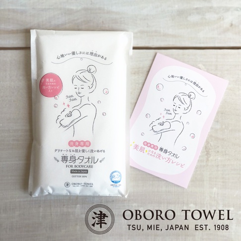 白色包裝的OBORO TOWEL三層紗專身潔膚巾，上面印有女性沐浴的插畫，文字標示「FOR BODYCARE」，並註明「Made in Japan」及「COTTON 100%」。旁邊附有一張粉紅色小卡，內容與潔膚巾包裝相似。