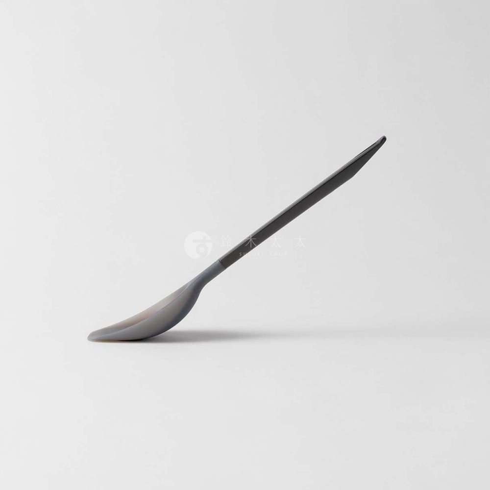 一個淺灰色的矽膠勺子，傾斜的拍攝角度，勺頭朝左下方，勺柄朝右上方向，勺柄上印有日文和英文的水印文字。