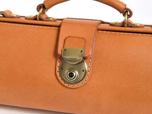 職人手作皮革橫長形單肩包，採用溫潤的棕褐色皮革，搭配復古黃銅色金屬鎖扣和鉚釘，整體呈現經典質感。