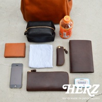 職人手作皮革Organ兩用方形口金托特包 G-55-H (共2種尺寸各3色) 的內容物展示，包含焦糖色皮革名片夾、黑色皮革化妝包、淺藍色布料、咖啡色皮革鑰匙包、咖啡色皮革長夾、iPhone手機、印有HAWAII字樣的薄荷糖盒，以及一個焦糖色皮革托特包。