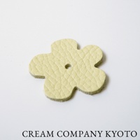 淺黃色皮革製成的四葉花造型吊飾，表面有細緻紋路，中心有一個小圓孔，邊緣為未經處理的皮革原色。