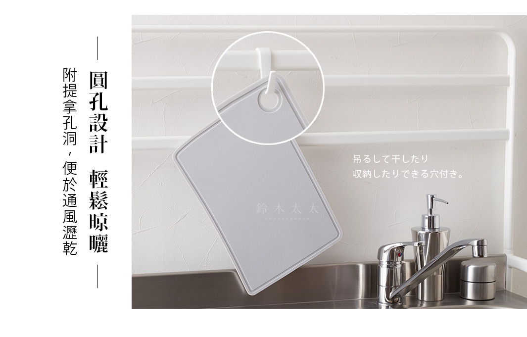 淺灰色矽膠砧板，帶圓孔設計，懸掛於廚房架上，旁邊為不鏽鋼水龍頭與皂液器。