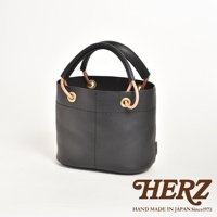 黑色皮革水桶包，配有加厚皮革提把、黃銅孔眼及連接繩。