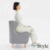 灰色布藝美姿調整座椅，立腰設計，配有四支木質椅腳，一位女士側身坐在座椅上。