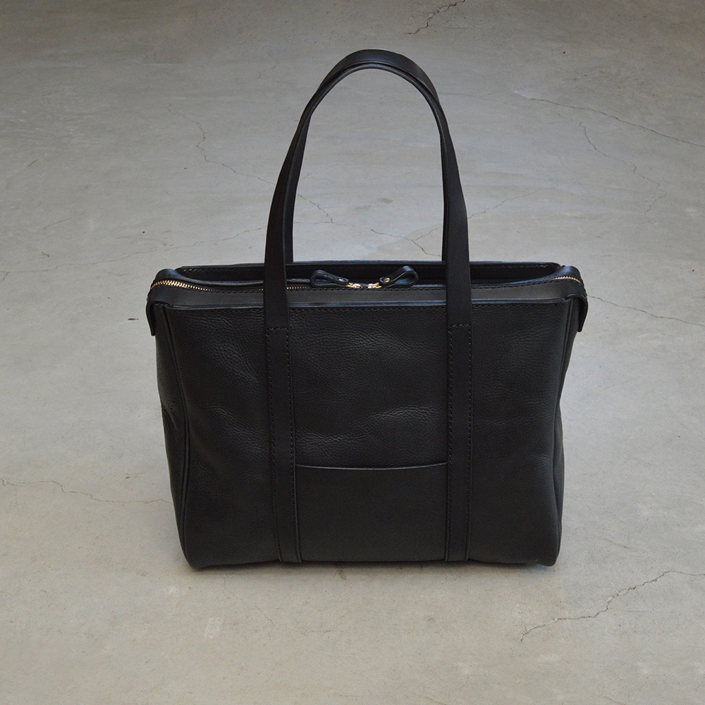 黑色職人手作皮革Organ肩背拉鍊托特包，包身呈現粒面紋理，配有雙提把、頂部拉鍊開合，以及正面一個水平置物口袋，整體簡潔大方。