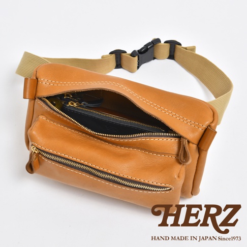 棕色皮革製作的兩用腰掛斜背包，設有拉鍊主袋和前袋，配有可調節的卡其色織帶和黑色塑膠扣。