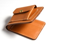焦糖色皮革雙折短夾，外附零錢袋，附有黃銅按扣，車縫線為白色。