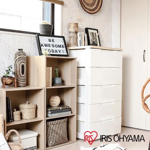 展示一個淺木色、四層開放式收納櫃，旁邊是白色六層抽屜櫃。收納櫃上擺放裝飾品，如花瓶、盆栽、書籍和藤編籃。