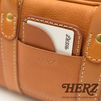 HERZ 品牌皮革兩用迷你波士頓包，正面設有卡槽，可見卡片上的 HERZ 標誌，包身壓印有 HERZ 字樣，下方為品牌標誌和「HAND MADE IN JAPAN Since1973」字樣。