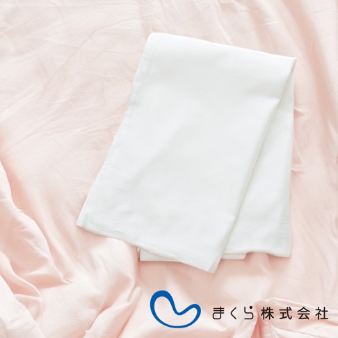 白色棉絲混紡美髮枕套，平整摺疊於粉紅色床單上。