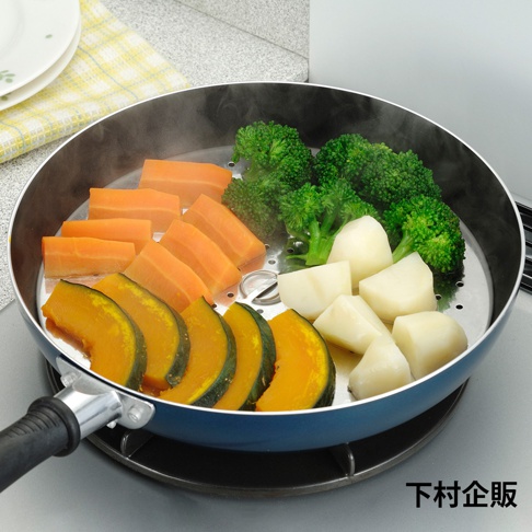 藍色平底鍋內置不鏽鋼蒸盤，盤中擺放著切塊的胡蘿蔔、花椰菜、南瓜片和馬鈴薯塊，蒸氣繚繞。