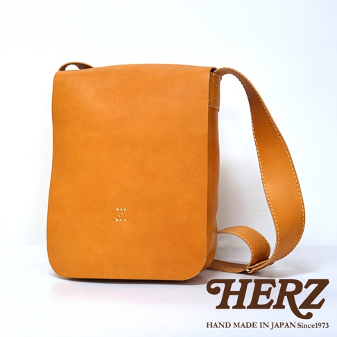 日本 HERZ 品牌皮革軟皮直式斜背包，深棕色，附有品牌 Logo，展現職人手作質感。