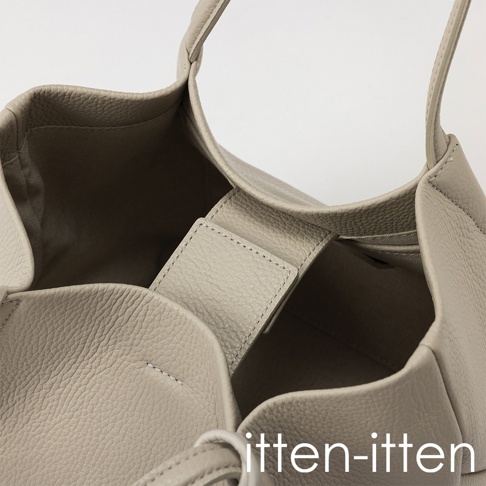 itten-itten 品牌名稱標誌，下方為一個灰褐色皮革托特包的特寫，展現其內部結構與材質紋理