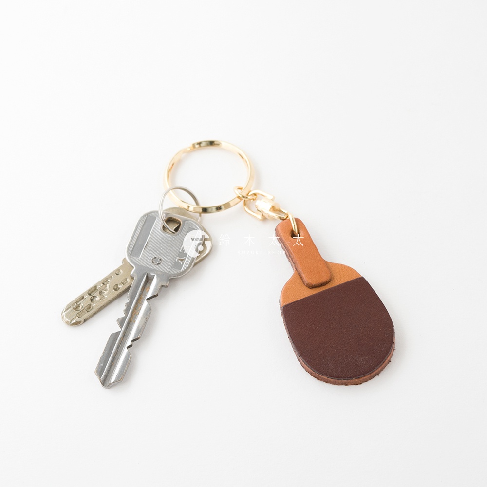 職人手作皮革桌球拍造型鑰匙圈，由淺棕色和深棕色皮革製成，搭配金色鑰匙圈。