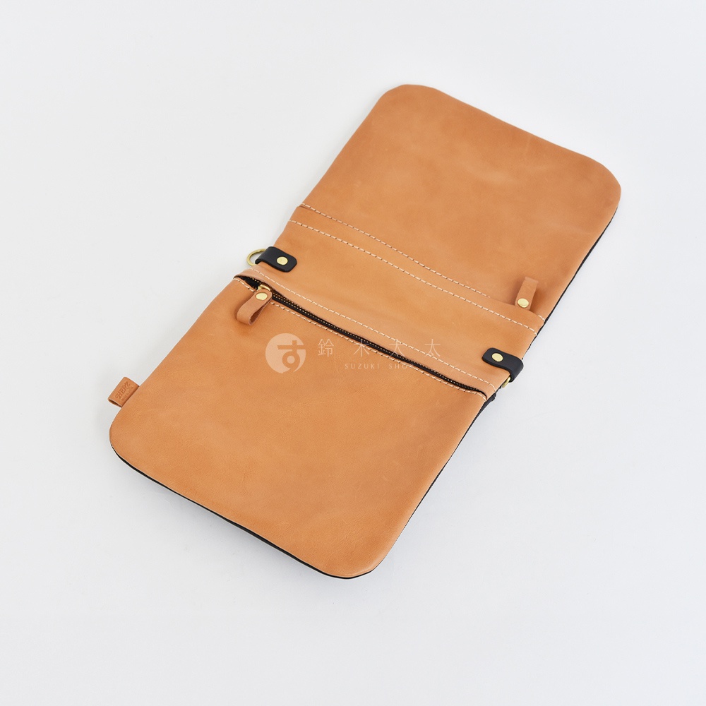 職人手作皮革翻轉雙色直式斜背包 CK-124，淺棕色皮革，兩側有黑色皮革裝飾，拉鍊開合，附有金屬 D 型環。