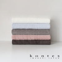 堆疊著五條不同顏色的浴巾，從上至下分別為白色、淺藍色、灰色、粉紅色和深棕色。浴巾質地蓬鬆柔軟。