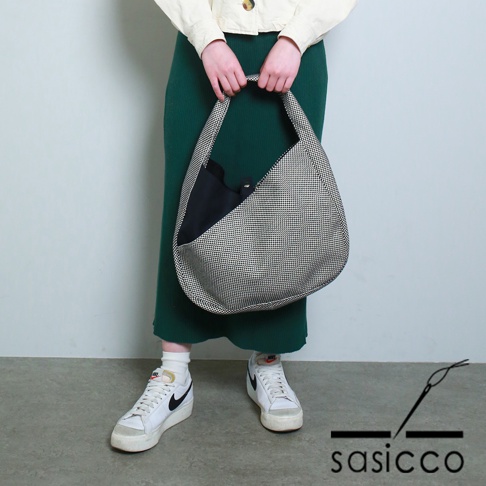 三河木綿刺子織製的半月包，織紋為細小的千鳥格，外層為黑白格紋，內裡為黑色，單肩背帶。