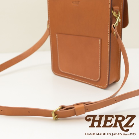 職人手作皮革單肩兩用小方包，採用棕色皮革製作，包身有明顯的縫線細節，前方設有方形貼袋，附有可調整長度的皮革揹帶及金色金屬扣環。