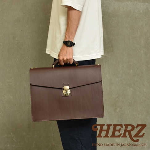深棕色皮革製成的兩用公事包，具有金色金屬鎖扣和提把，包身結構堅固，適合商務使用。