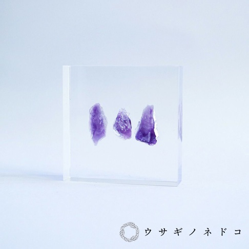 透明壓克力方塊中包裹著三塊紫水晶切片，呈現紫色漸層與晶體紋理。