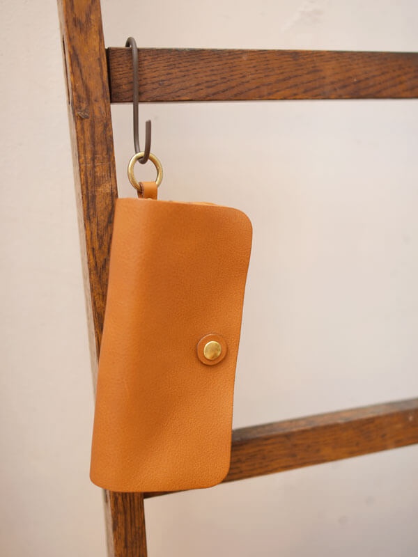 職人手作皮革旅行用長夾，採用溫潤的棕褐色皮革，配有金色釦飾與金屬掛環，設計簡潔實用。