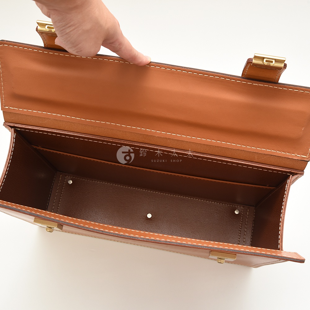 職人手作皮革兩用機師箱，呈現經典棕色調，以真皮材質製作，內襯亦為皮革。箱子內部空間寬敞，附有隔層，配有金屬鎖扣與黃銅色五金配件，縫線細緻。