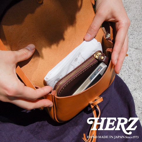 棕色皮革流蘇側背包，內有拉鍊口袋，可放置手機，材質為真皮，手工製作，風格簡約。