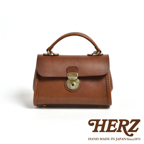 職人手作皮革迷你手提包，顏色為棕色，材質為皮革，配有金屬鎖扣和提把。