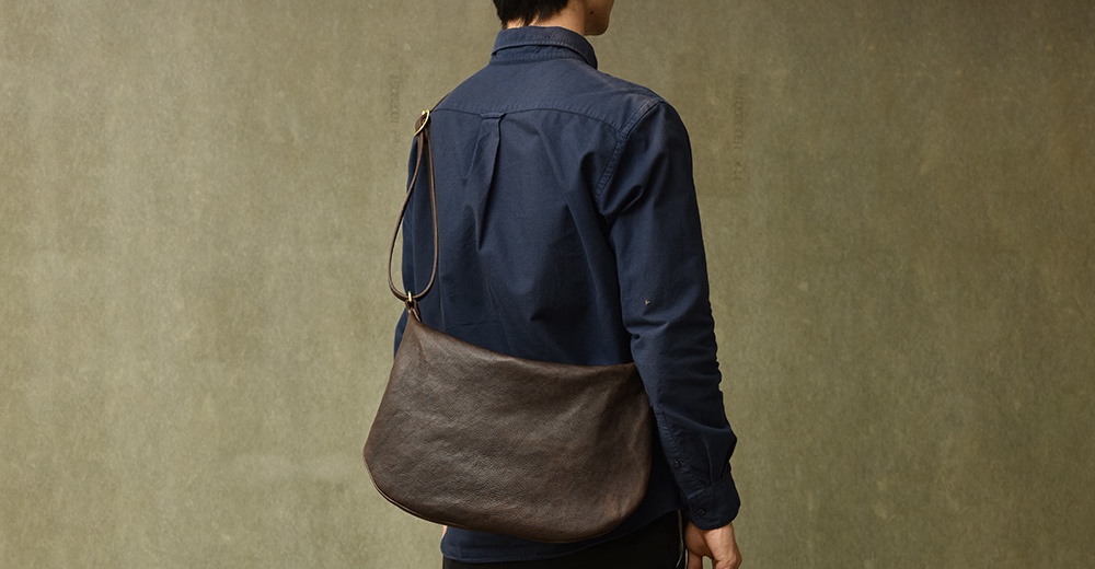 職人手作皮革Organ單肩半月包，深棕色，半月形包身，皮質柔軟，搭於模特兒肩上。