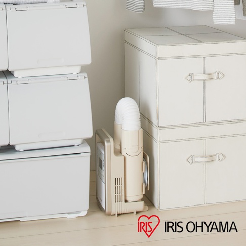 米白色強力被褥乾燥機 KFK301，配有白色伸縮軟管，旁邊堆疊著米白色帶有縫線和提把的儲物箱，整體呈現簡潔的家居風格。