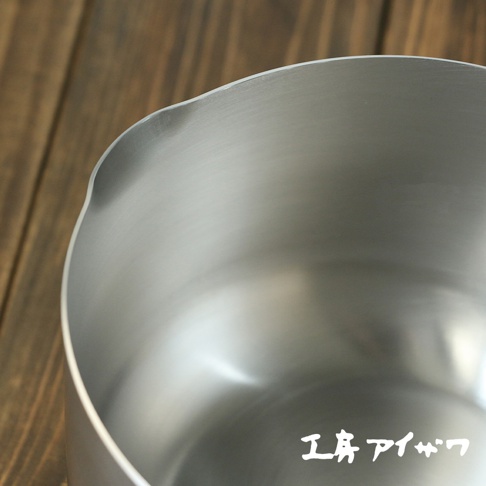 不鏽鋼雙口牛奶鍋，鍋身呈現銀色，材質為不鏽鋼，頂部邊緣有兩個方便傾倒的鍋嘴。