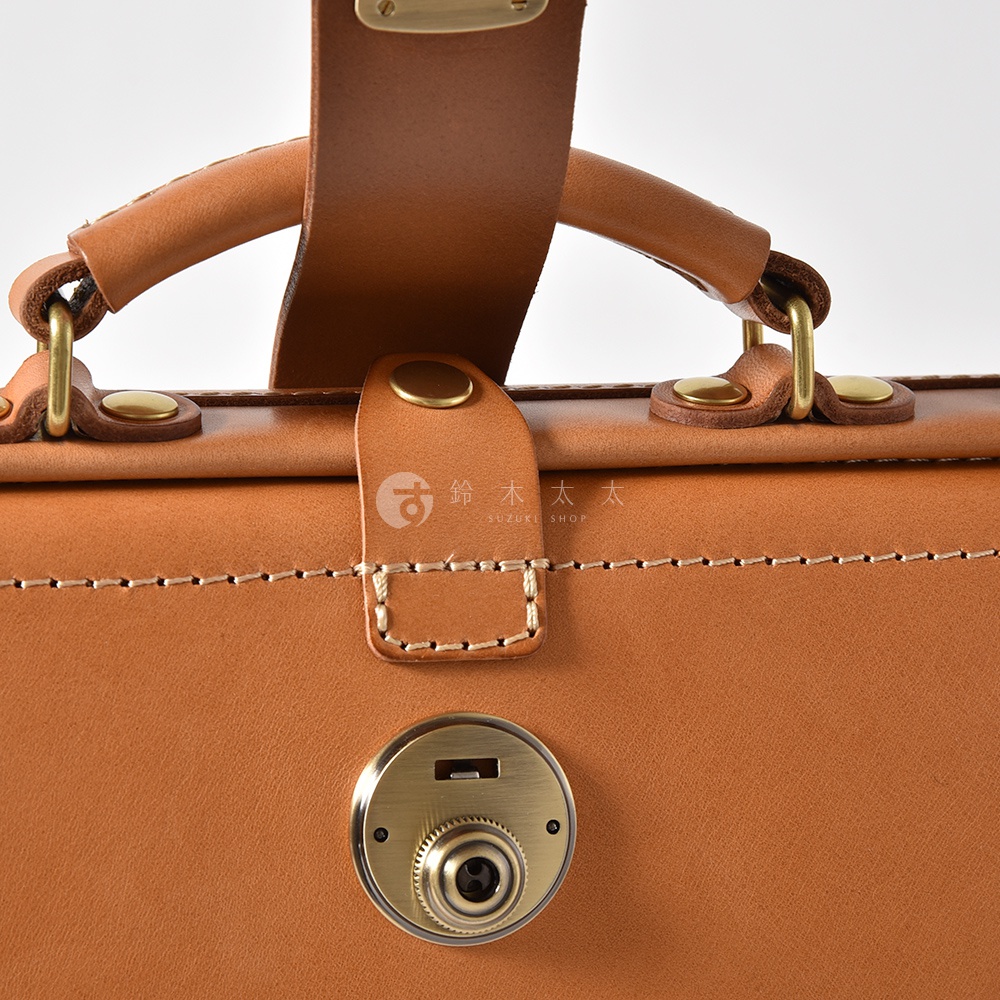 職人手作皮革軟式杜勒斯三用背包，採用棕色柔軟皮革製成，配有黃銅色金屬鎖扣、旋鈕鎖和縫線細節，展現精緻工藝。