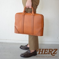 職人手作咖啡色皮革Organ商務公事包，配有雙提把和拉鍊封口，皮革材質，整體呈現簡約大方的設計。
