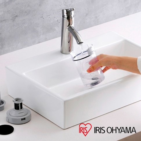 一個透明集塵杯正在被沖水，旁邊是一個白色水槽，水槽旁有吸塵器的灰色配件。